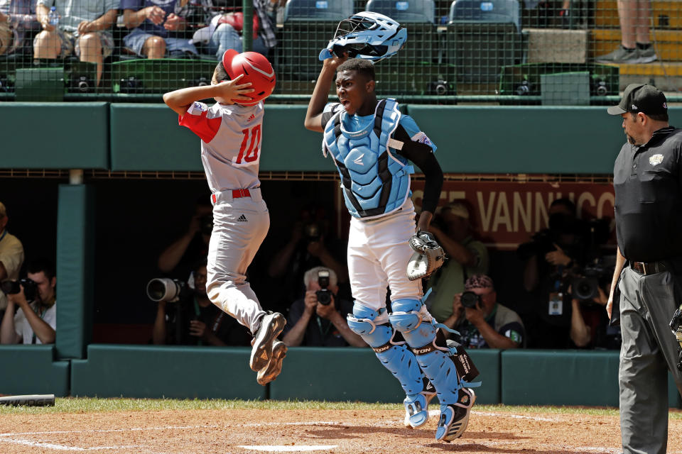 Curacao catcher Jurdrick Profar, right, begins to celebrate after getting the final out of a 5-4 win over Japan in the International Championship baseball game at the Little League World Series tournament in South Williamsport, Pa., Saturday, Aug. 24, 2019. (AP Photo/Gene J. Puskar)