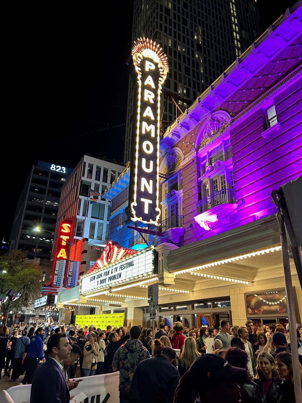 Glowing sign of Paramount Theatre and crowd outside Netflix premiere