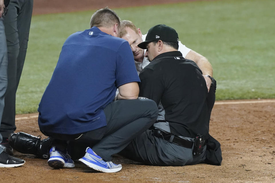 MLB home plate umpire Jim Reynolds is assisted on the field after he was hit by a pitch in the eighth inning of a baseball game against the Miami Marlins, Tuesday, Aug. 30, 2022, in Miami. (AP Photo/Marta Lavandier)