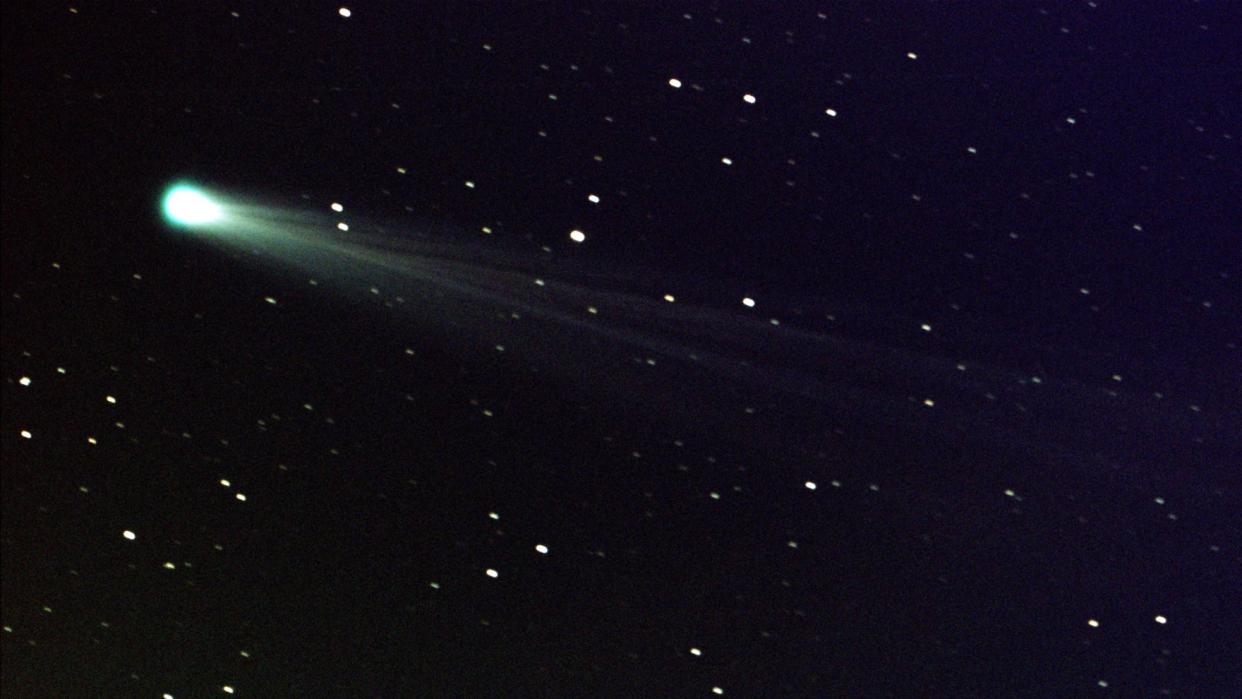  A green comet seen streaking through the night sky with an icy tail dragging behind it. 