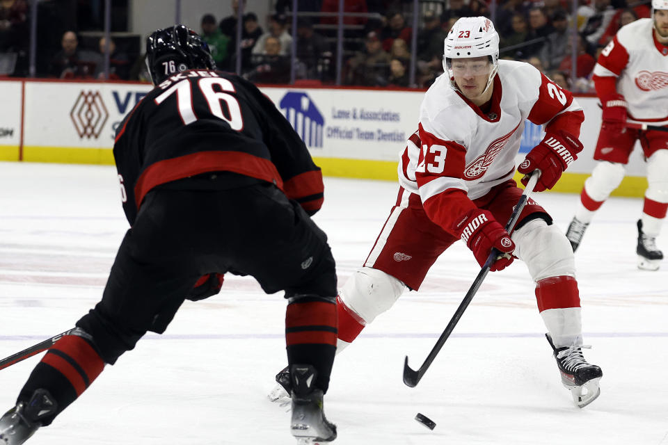 Detroit Red Wings' Lucas Raymond (23) chips the puck past Carolina Hurricanes' Brady Skjei (76) during the first period of an NHL hockey game in Raleigh, N.C., Friday, Jan. 19, 2024. (AP Photo/Karl B DeBlaker)