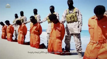 Islamic State militants stand behind what are said to be Ethiopian Christians along a beach in Wilayat Barqa, in this still image from an undated video made available on a social media website on April 19, 2015. REUTERS/Social Media Website via Reuters TV/File Photo
