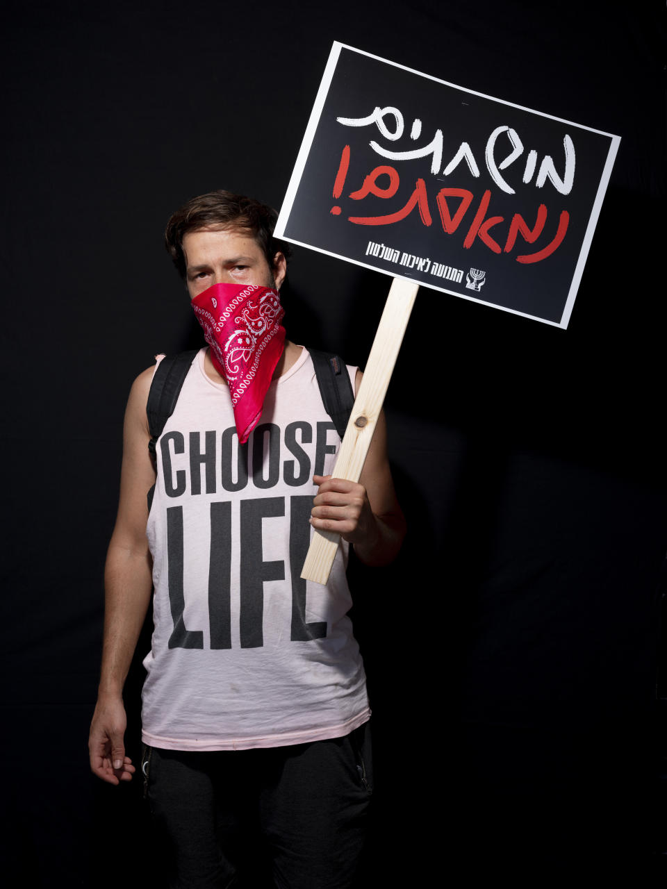 Dan Lantzet, 32, poses for a photo during a protest against Israel's Prime Minister Benjamin Netanyahu, outside his residence in Jerusalem, Thursday, July 23, 2020. Hebrew on sign reads, "Corrupted, we are fed up". The wave of colorful and combative demonstrations against Netanyahu and his perceived failure to handle the country's deepening economic crisis have been characterized by youth. With flags, facemasks, drums, placards and an assortment of props, thousands have been taking to the streets to demand change in a variety of unique ways. (AP Photo/Oded Balilty)