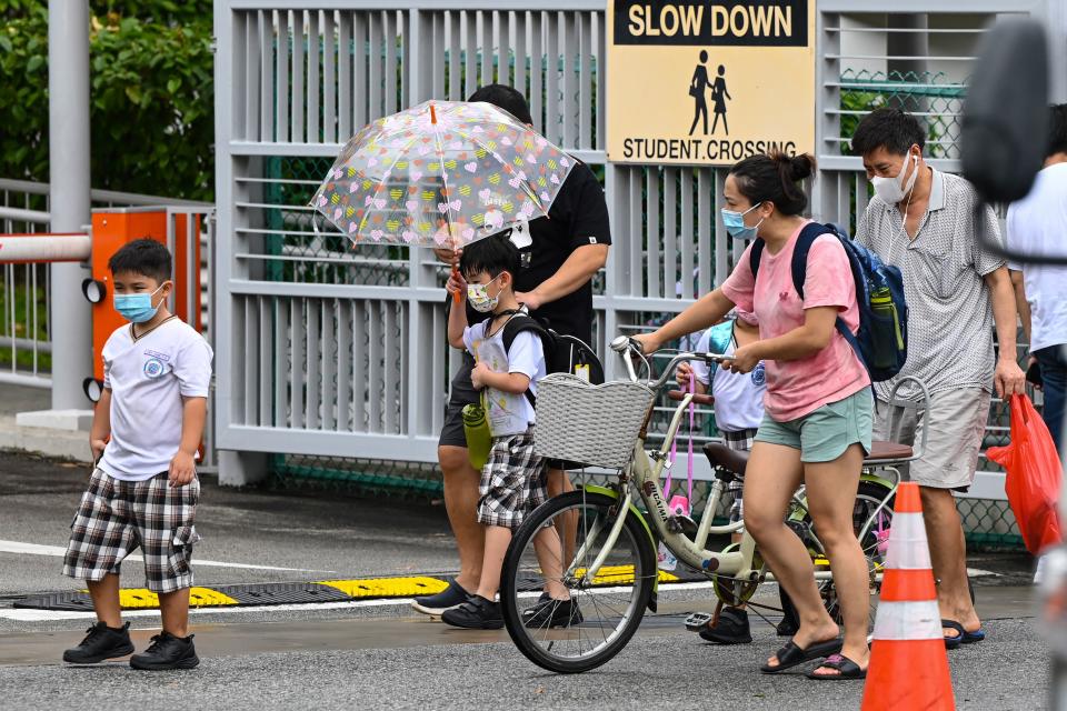 Children walk home with their guardians after school in Singapore on May 17, 2021, as the country prepares to shut all schools and switch to home-based learning until the end of the term due to a rise in the number of Covid-19 coronavirus cases. (Photo by Roslan RAHMAN / AFP) (Photo by ROSLAN RAHMAN/AFP via Getty Images)