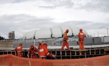 Workers work on areas of infrastructure next to the construction site of the Arena das Dunas stadium, in Natal May 10, 2014. REUTERS/Nuno Guimaraes