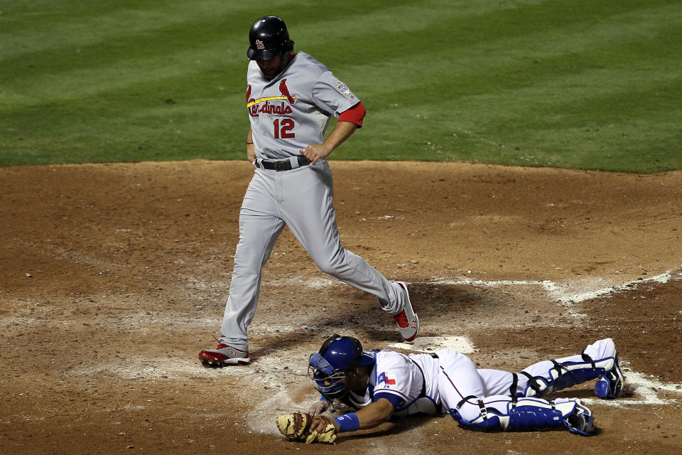 ARLINGTON, TX - OCTOBER 22: Lance Berkman #12 of the St. Louis Cardinals scores in front of Yorvit Torrealba #8 of the Texas Rangers after an error by Mike Napoli #25 of the Texas Rangers in the fourth inning during Game Three of the MLB World Series at Rangers Ballpark in Arlington on October 22, 2011 in Arlington, Texas. (Photo by Ezra Shaw/Getty Images)