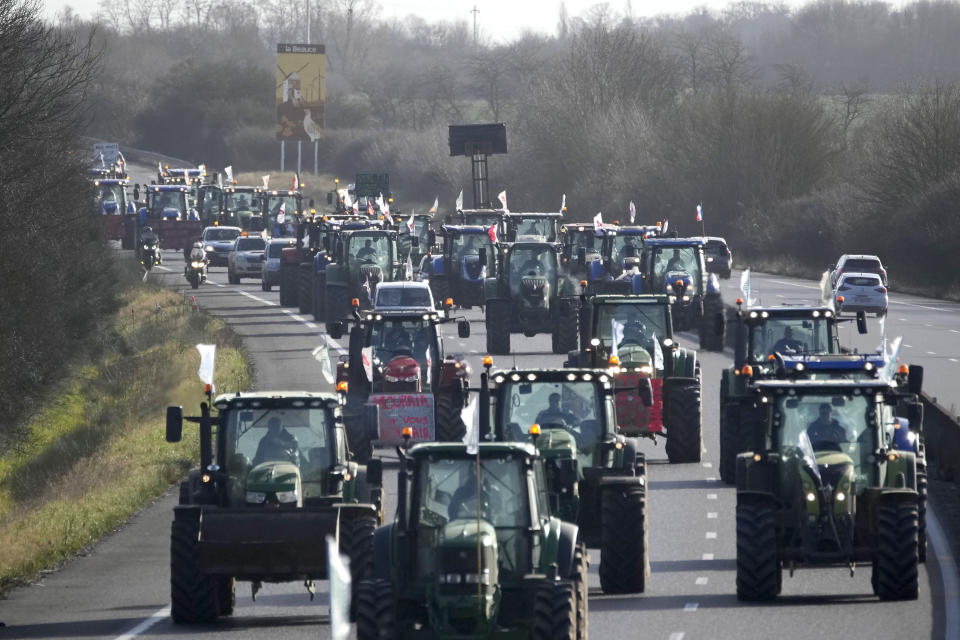 Farmers drive their tractors on their way to a blockade on a highway, Friday, Jan. 26, 2024 near Saint-Arnoult, south of Paris. Protesting farmers shut down long stretches of some of France's major motorways on Friday, using their tractors to block and slow traffic and squeeze the government ever more tightly to cede to their demands that growing and rearing food should be made easier and more lucrative. (AP Photo/Christophe Ena)
