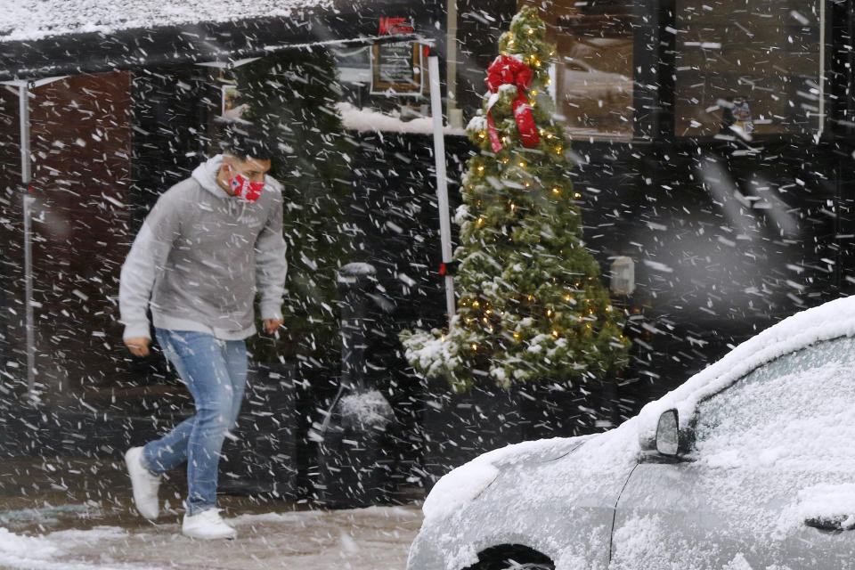 A man runs through heavy snow, Saturday, Dec. 5, 2020, downtown in Marlborough, Mass. The northeastern United States is seeing the first big snowstorm of the season. (AP Photo/Bill Sikes)