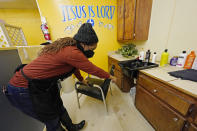Belinda Smith, owner of Styles of Essence, a hair salon in south Jackson, Miss., points out the gallons of water stored under each sink, available to use for rinsing clients hair because of the uncertainty of the city's water service, Wednesday, Jan. 26, 2022. The city's ongoing water woes sometimes requires the area water to be shut off without warning. (AP Photo/Rogelio V. Solis)
