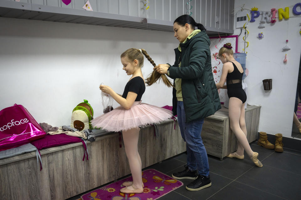 A mother prepares her daughtr to practice in a ballet studio in a bomb shelter in Kharkiv, Ukraine, Monday, March 18, 2024. In northeast Ukraine, a dance studio that doubles as a bomb shelter is an escape from the horrors of war for about 20 young girls. The Princess Ballet Studio in Kharkiv is a spartan, windowless room, but practicing underground means they can dance through the almost hourly air raid alerts. (AP Photo/Efrem Lukatsky)