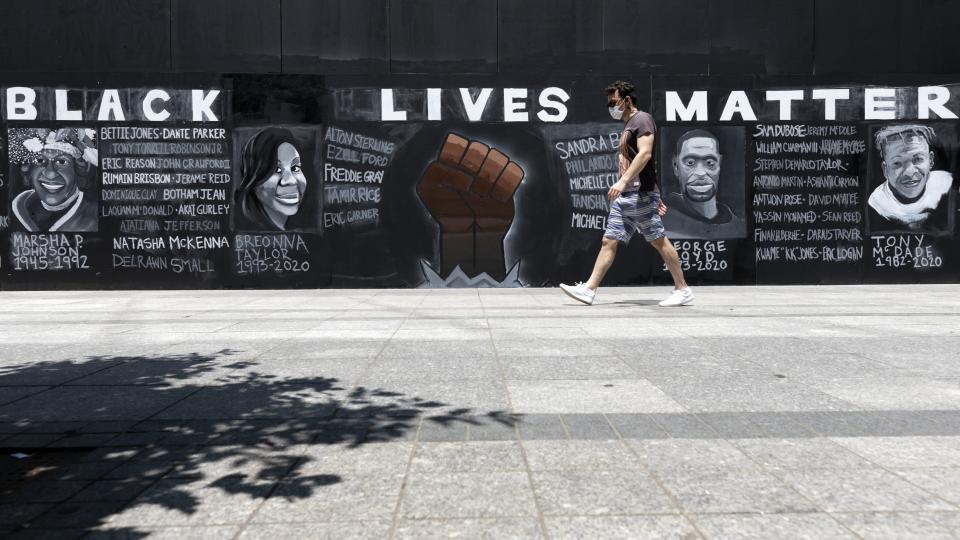 FILE - In this June 6, 2020, file photo, a man walks past a "Black Lives Matter" mural painted on the boarded-up Apple Store, in Boston. Black Lives Matter has gone mainstream — and black activists are carefully assessing how they should respond. (AP Photo/Michael Dwyer, File)