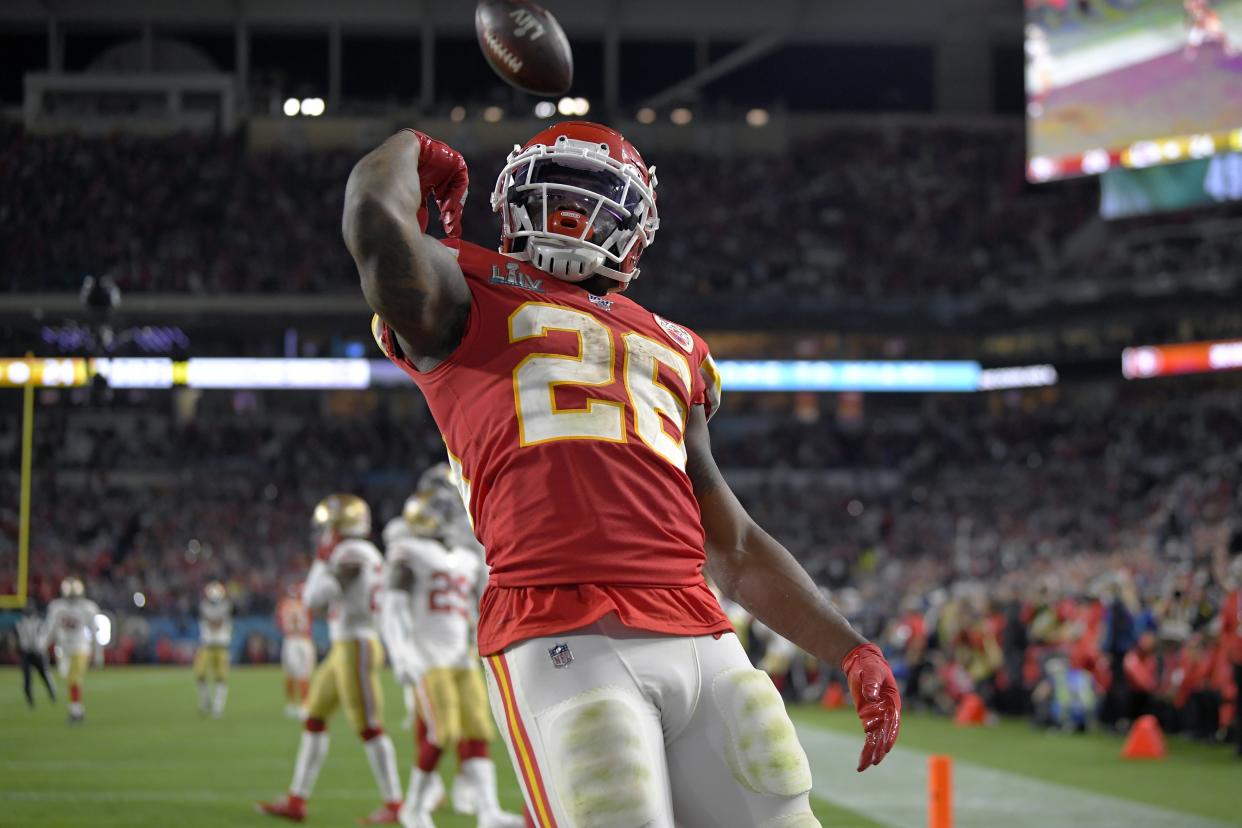 Damien Williams flexes after flipping the football over his head while wearing a red Chiefs uniform.