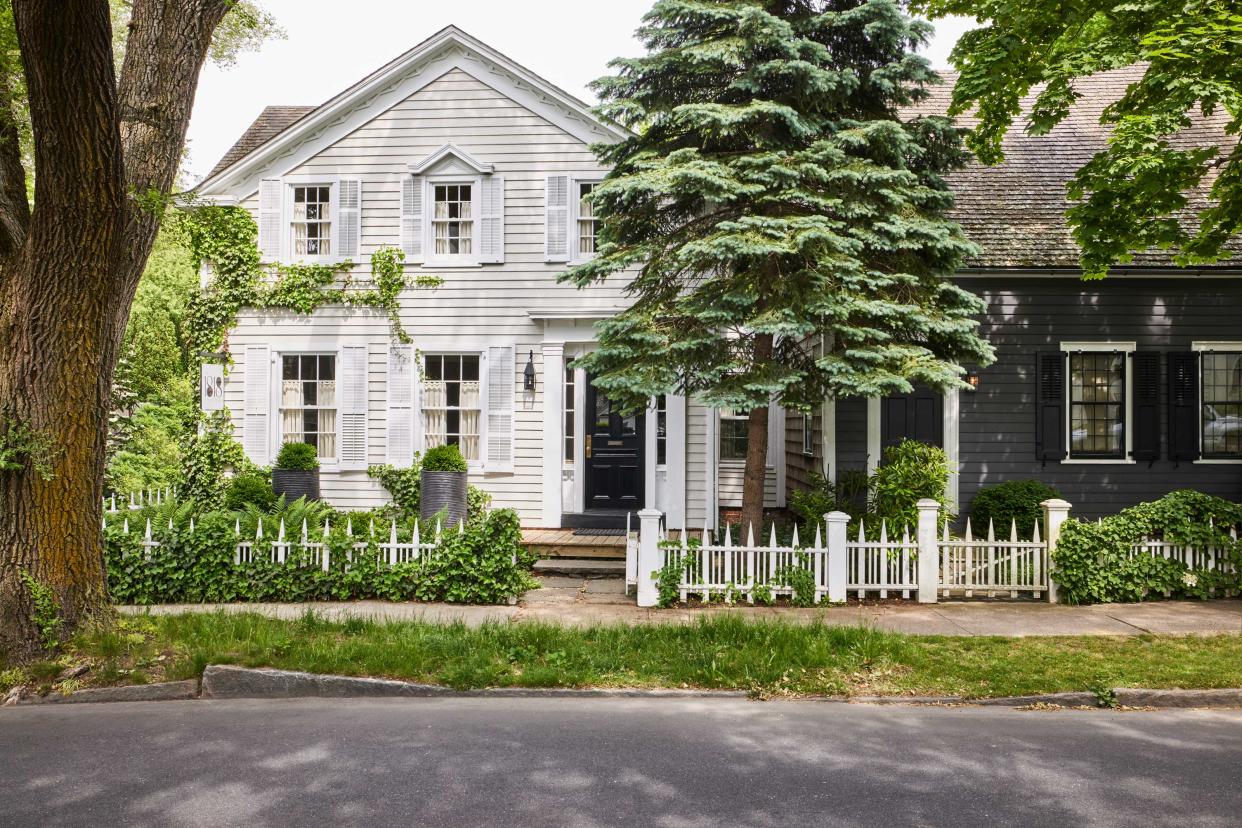  a classic shiplap house with a tree and planting outside 