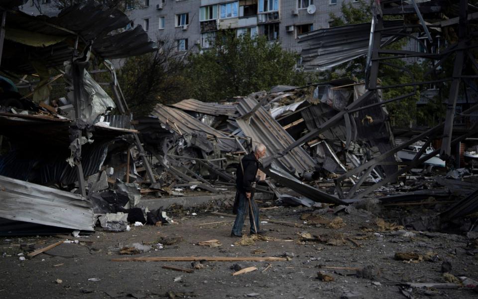An elderly man walks past a car shop that was destroyed after a Russian attack in Zaporizhzhia -  Leo Correa/AP