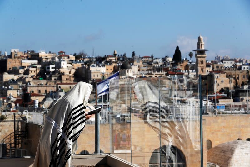 A Jewish worshipper prays on a balcony overlooking the Western Wall as a down-sized priestly blessing, a traditional prayer which usually attracts thousands of worshippers on Passover takes place amid the coronavirus outbreak in Jerusalem's Old City