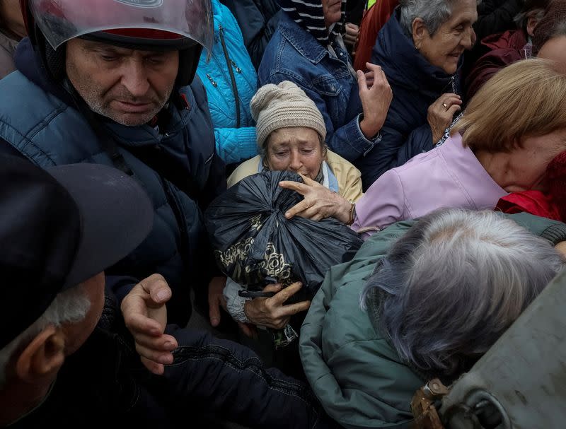 Local residents crowd near a car distributing humanitarian aid in the town of Balakliia