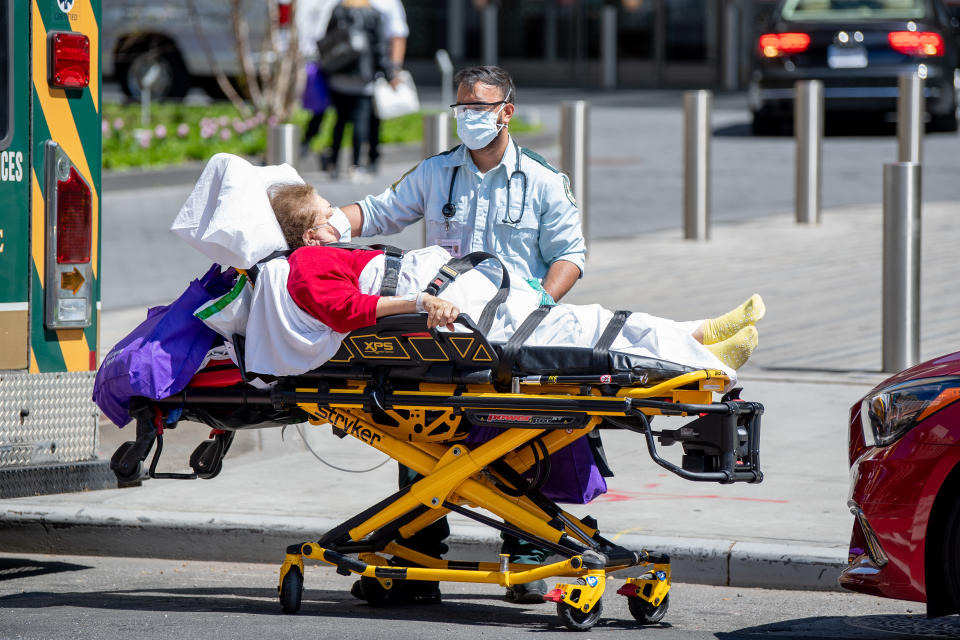 A medical staff member in a mask with a patient outside of an ambulance amid the COVID-19 outbreak on April 19, 2020 in New York City. (Photo by Roy Rochlin/Getty Images)