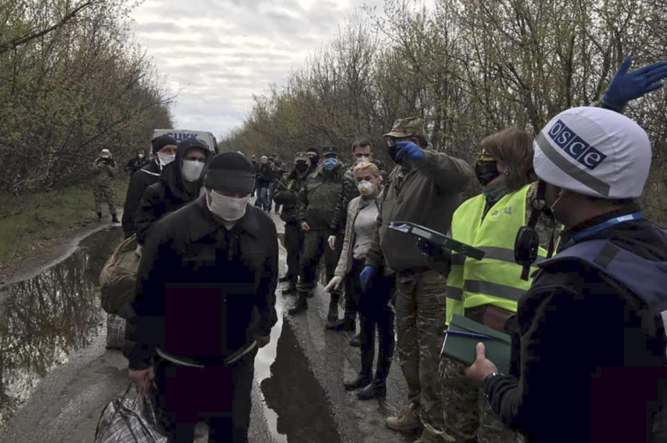 Russia-backed separatists war prisoners, left, wearing masks to protect against coronavirus walk during a prisoner exchange, in Donetsk region, eastern Ukraine, Thursday, April 16, 2020. Ukrainian forces and Russia-backed rebels in eastern Ukraine have begun exchanging prisoners in a move aimed at ending their five-year long war. (Ukrainian Presidential Press Office via AP)