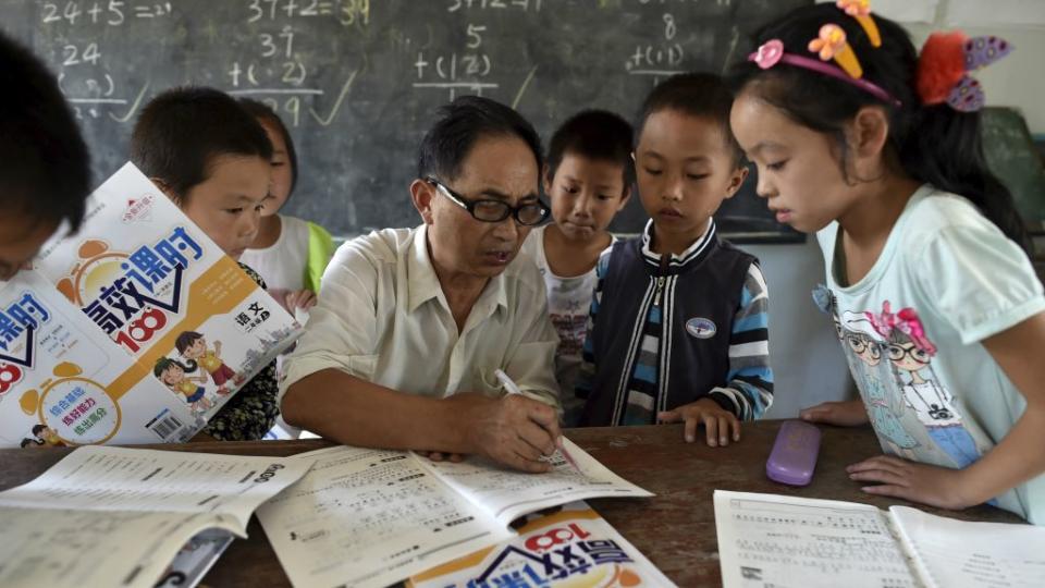 A teacher (C) speaks to students inside a classroom of Dalu primary school in Gucheng township of Hefei, Anhui province, China, September 8, 2015. The school, opened in 2006 and has never acquired a legal license, may face a shutdown order from the government. There are currently over 160 students in the school, mostly "leftover children", whose parents left their hometown to earn a living, local media reported.