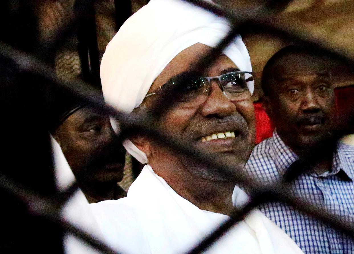 Sudan's former president Omar Hassan al-Bashir smiles as he is seen inside a cage at the courthouse where he is facing corruption charges, in Khartoum (REUTERS)