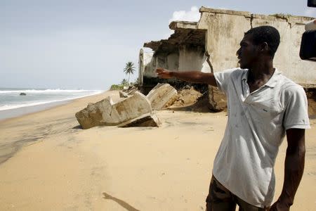 A resident talks near abandoned houses damaged by erosion on a beach in Grand-Lahou on the southern Ivory Coast, in this June 8, 2010 file photo. REUTERS/Luc Gnago