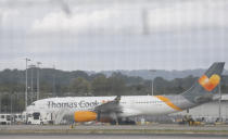 Seen through a perimeter fence, a Thomas Cook aircraft on the tarmac at Gatwick Airport, England, Monday, Sept. 23, 2019. British tour company Thomas Cook collapsed early Monday after failing to secure emergency funding, leaving tens of thousands of vacationers stranded abroad. (AP Photo/Alastair Grant)