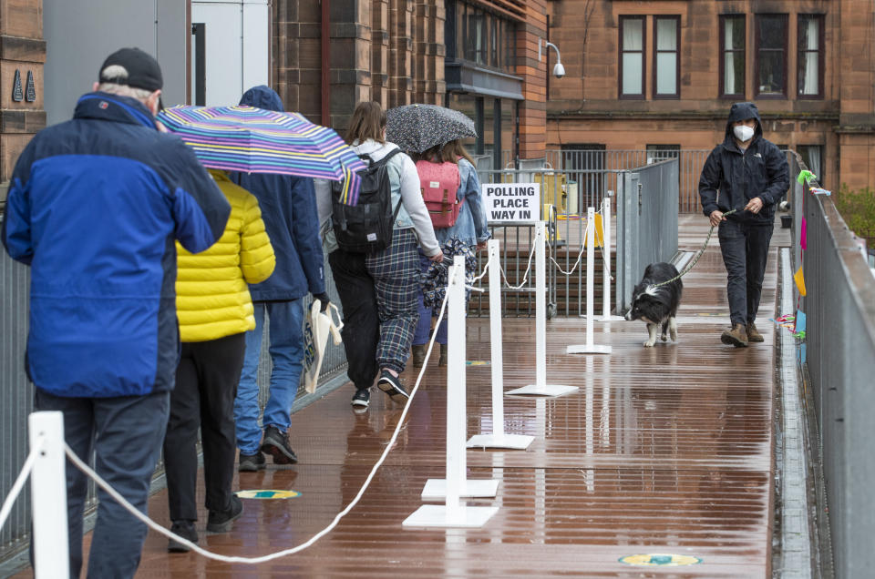 People queue to vote outside a polling station in Glasgow, Scotland, Thursday May 6, 2021. Scots are heading to the polls to elect the next Scottish Government - though the coronavirus pandemic means it could be more than 48 hours before all the results are counted. (Jane Barlow/PA via AP)