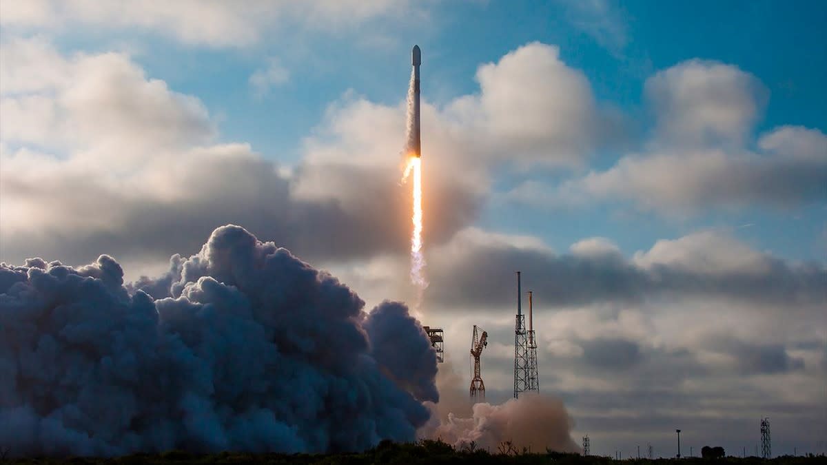  A white rocket lifts off under a cloudy sky. 