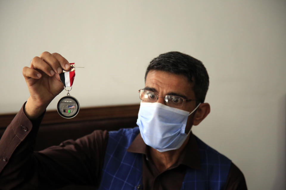 In this Friday, April 30, 2021, photo Ayazudin Hilal, 40, a former Afghan interpreter for the U.S. hold his medal during an interview to The Associated Press after a protest against the U.S. government and NATO in Kabul, Afghanistan. (AP Photo/Mariam Zuhaib)