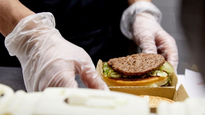 gloved hands holding burger