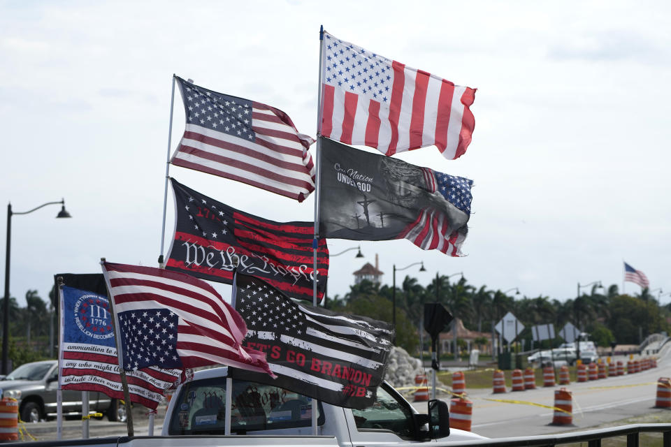 Flags fly from a former President Donald Trump supporter's truck outside of former President Donald Trump's Mar-a-Lago estate, Monday, March 20, 2023, in Palm Beach, Fla. (AP Photo/Lynne Sladky)