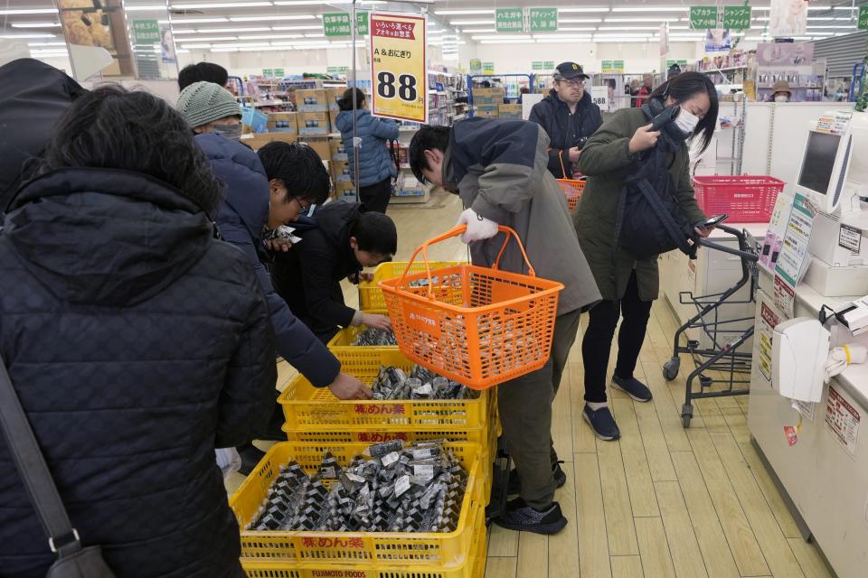 A woman, right, goes through a cashier as others shop for food, left, at a supermarket that has resumed its business with shorter hours after Monday's earthquake, in Wajima in the Noto peninsula, facing the Sea of Japan, northwest of Tokyo, Saturday, Jan. 6, 2024. (AP Photo/Hiro Komae)