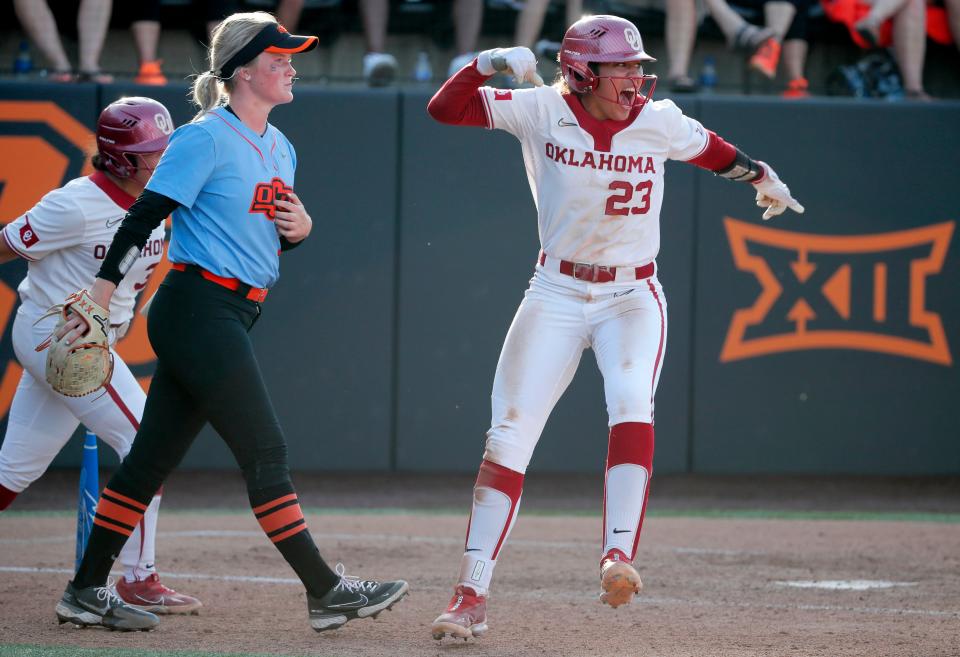 Oklahoma's Tiare Jennings (23) celebrates beside Oklahoma State's Kelly Maxwell (28) after scoring a run in the seventh inning of a Bedlam college softball game between the Oklahoma State University Cowgirls (OSU) and the University of Oklahoma Sooners (OU) in Stillwater, Okla., Saturday, May 6, 2023. Oklahoma won 4-2. 