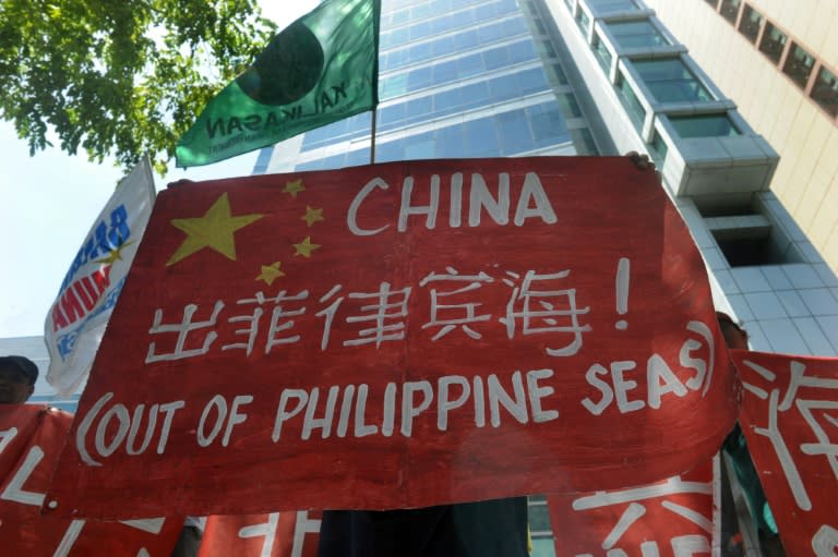 Filipino environmental activists display placards during a rally outside China's consular office in Manila on May 11, 2015 against China's reclamation and construction activities on islands and reefs in the Spratly Group of the South China Sea