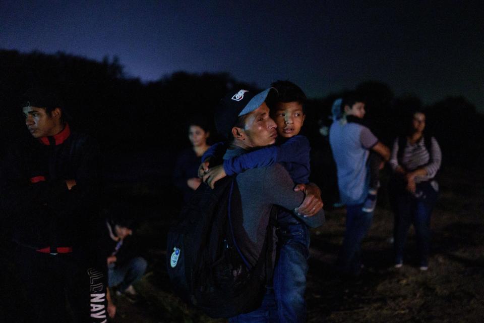 Honduran Eric Villanueva, 31, holds his son Eric, 7, while waiting to be led to a United States Border Patrol processing area after crossing the US-Mexico border on a raft into the United States in Roma, Texas late on July 9, 2021. / Credit: PAUL RATJE/AFP via Getty Images