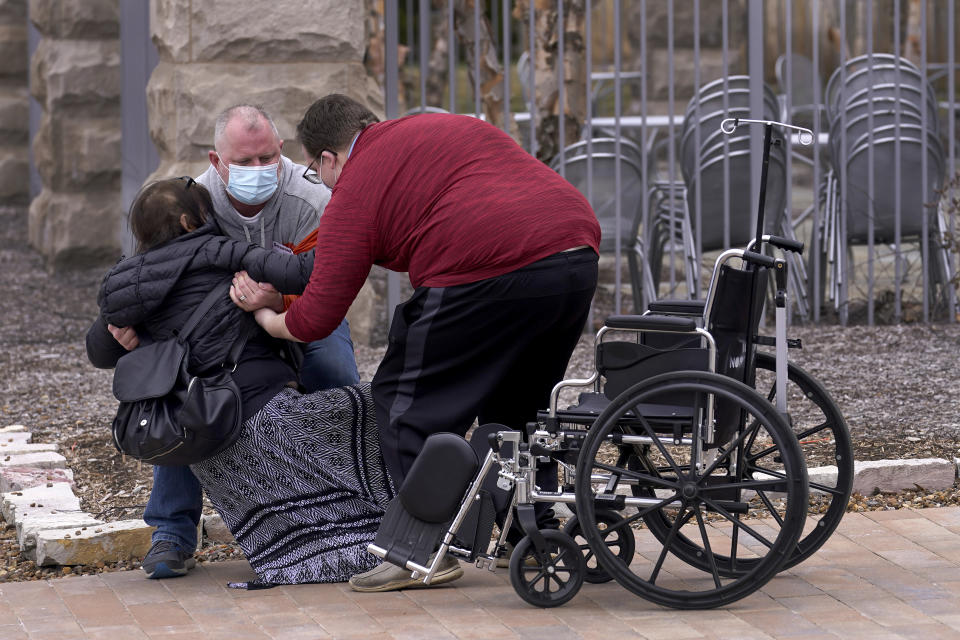 Lucas Christensen, right, helps Rodney Wegg pick up his wife, Kari, after she collapsed after visiting IU Health North Hospital for her second COVID shot in Carmel, Ind., on Monday, March 22, 2021. (AP Photo/Charles Rex Arbogast)