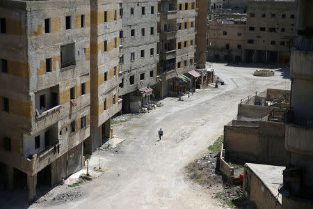 Abu Malek, one of the survivors of a chemical attack in the Ghouta region of Damascus that took place in 2013, uses his crutches to walk along a street in the Ghouta town of Ain Tarma, Syria April 7, 2017. REUTERS/Bassam Khabieh