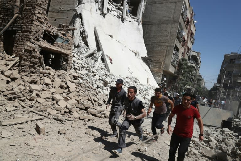 Syrians run for cover during reported government air strikes in the rebel-held town of Douma, east of the capital Damascus