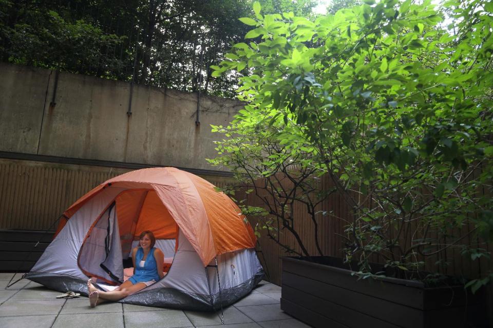 Kathleen Boyle poses for a picture in a tent on the patio of her room at the Affina Hotel in New York, Thursday, Aug. 15, 2013. A couple of New York City locales are offering an unusual option _ the chance to sleep outdoors, incredibly comfortably. It’s an urban take on “glamping,” where hotel comforts are taken outside. (AP Photo/Seth Wenig)