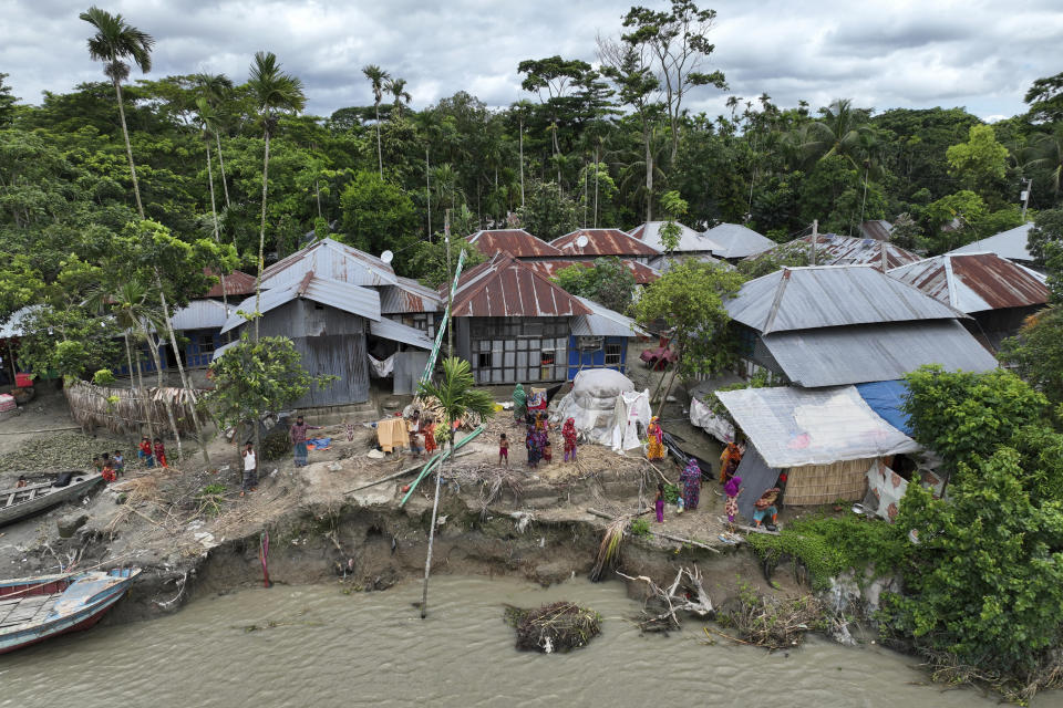 Families live along an embankment that has some erosion caused by the Meghna River in the Ramdaspur village in the Bhola district of Bangladesh on July 5, 2022. Mohammad Jewel and Arzu Begum were forced to flee the area last year when the river flooded and destroyed their home. (AP Photo/Mahmud Hossain Opu)