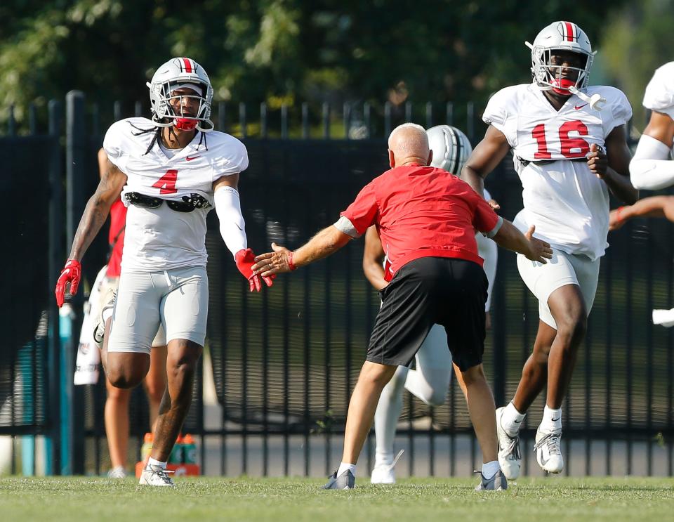 Ohio State Buckeyes defensive coordinator Kerry Coombs high fives cornerbacks Lejond Cavazos (4) and Ohio State Buckeyes Ryan Watts (16) during football training camp at the Woody Hayes Athletic Center in Columbus on Friday, Aug. 6, 2021. 