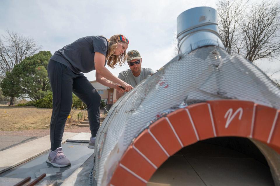Stoke Pizza owners Bre and Wes Latka secure insulation on their new wood-fired pizza oven trailer that will help replace an oven trailer that was stolen in September.