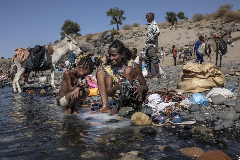 Tigray refugees who fled the conflict in the Ethiopia's Tigray arrive wash their clothes on the banks of the Tekeze River on the Sudan-Ethiopia border, in Hamdayet, eastern Sudan, Tuesday, Dec. 1, 2020. (AP Photo/Nariman El-Mofty)