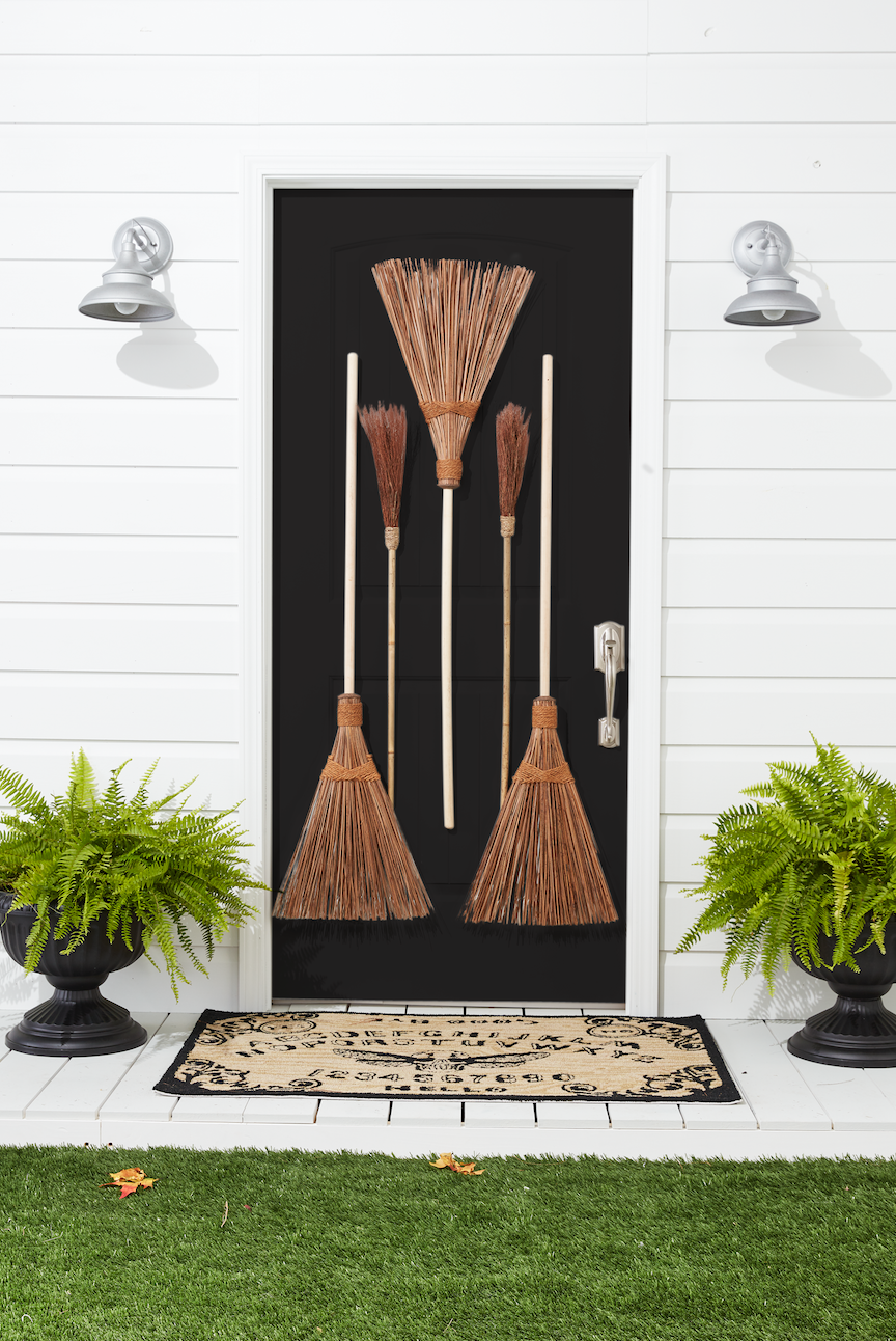 <p>Pay homage to everyone's favorite Halloween character with this fun idea. All you need are a few vintage brooms and a witchy attitude to make it happen!</p><p><strong>Assemble the Brooms: </strong>Drill a small hole in the handle of two large outdoor brooms. Hammer five small nails in front door. Hang two brooms, right sides up, through holes. Hang a third large broom and two small “witches' brooms" by threading the bristles over the remaining three nails. </p>