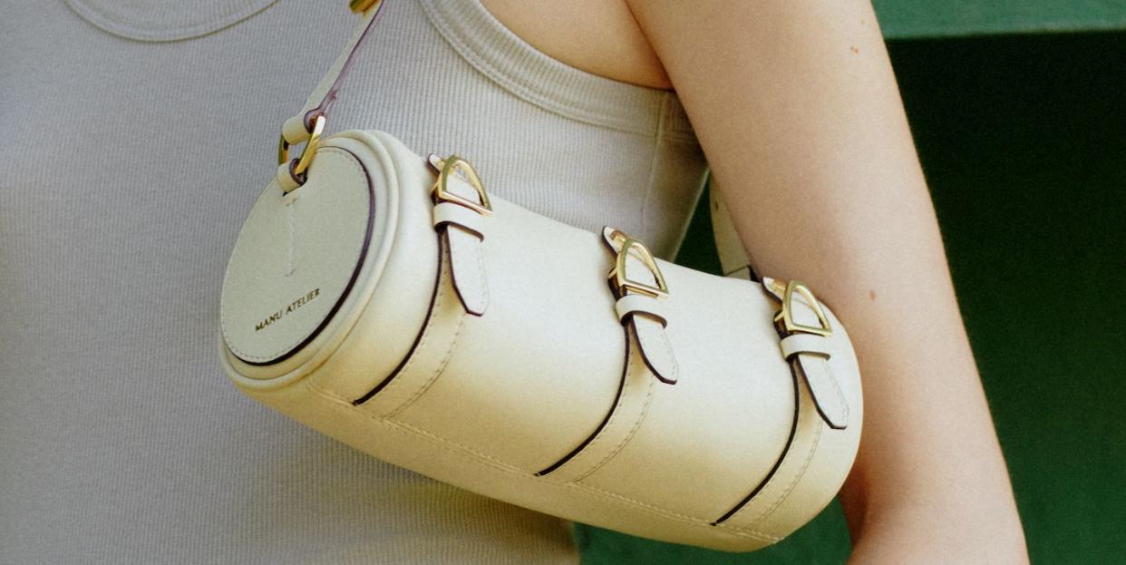 a woman in a tank top with a pale yellow bag slung on the arm