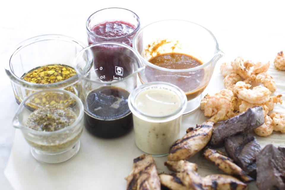 This July 29, 2013 photo shows, clockwise from top right, marinades of orange ginger, white wine mustard, lemon herb and garlic balsamic in Concord, N.H. At center is maple soy. On the meat, from top, are chipolte lime, red wine and rosemary and spicy hoisin. (AP Photo/Matthew Mead)