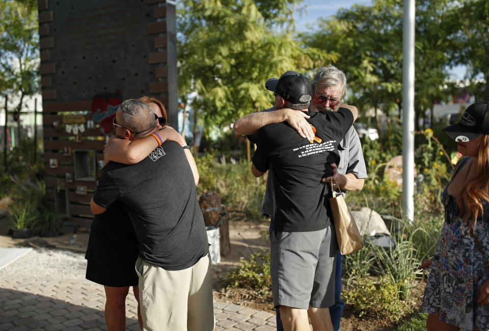 In this Friday, Sept. 28, 2018, photo, people embrace at a memorial garden for victims of the Oct. 1, 2017 mass shooting in Las Vegas. The small garden in downtown Las Vegas is home to photos, crosses, ribbons and dozens of other items placed in memory of the 58 people who were killed Oct. 1, 2017, in the deadliest mass shooting in modern U.S. history. (AP Photo/John Locher)