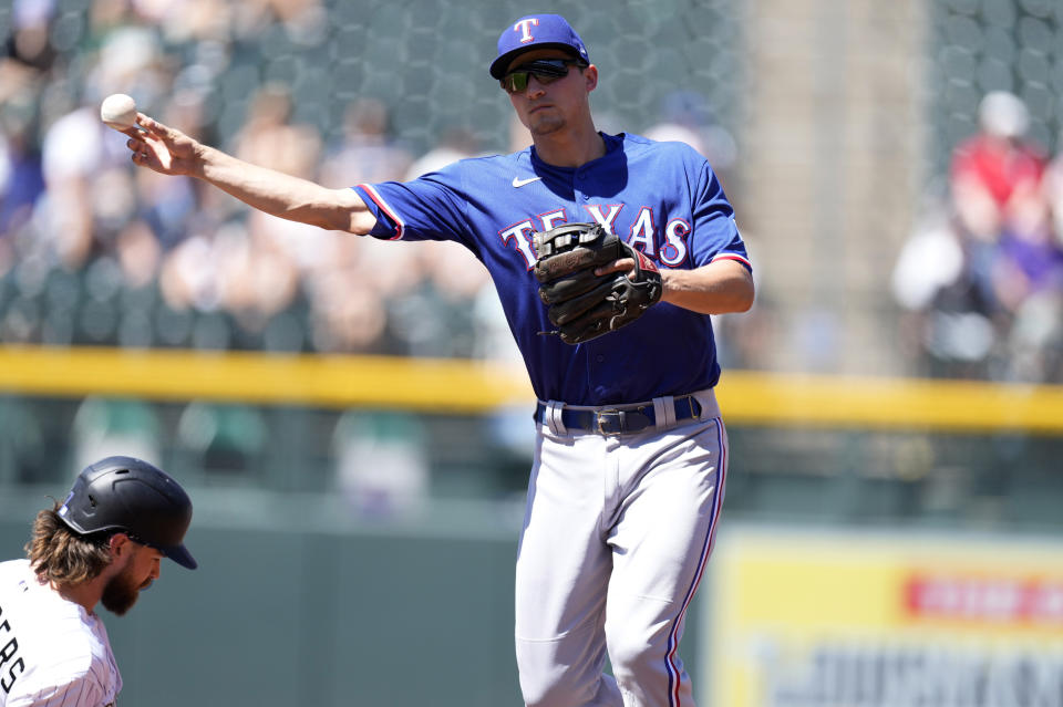 Texas Rangers shortstop Corey Seager, right, throws to first base after forcing out Colorado Rockies' Brendan Rodgers at second base on the front end of a double play hit into by C.J. Cron to end the first inning of a baseball game Wednesday, Aug. 24, 2022, in Denver. (AP Photo/David Zalubowski)