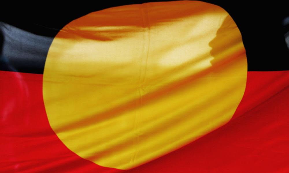 A woman is silhouetted behind the Aboriginal flag