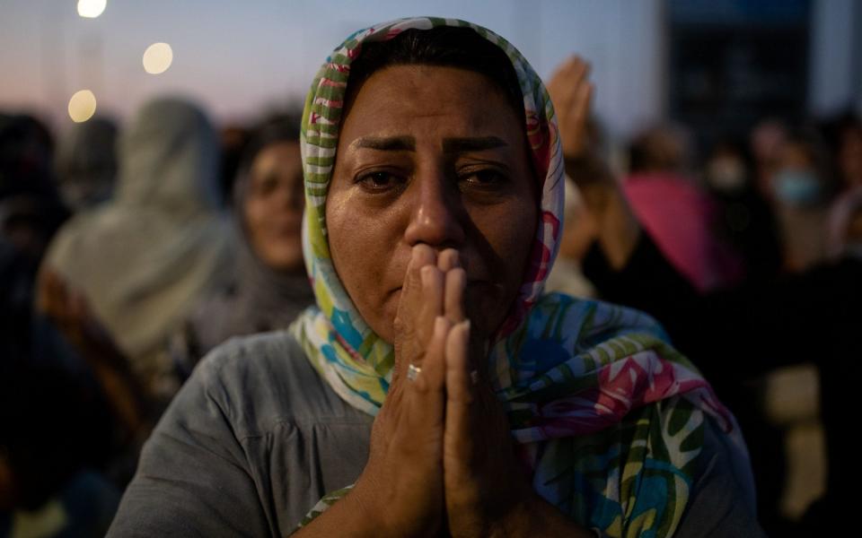 A woman reacts as refugees and migrants from the destroyed Moria camp pray near a new temporary camp where they will be accommodated, on the island of Lesbos, Greece, September 13, 2020. REUTERS/Alkis Konstantinidis - ALKIS KONSTANTINIDIS/REUTERS